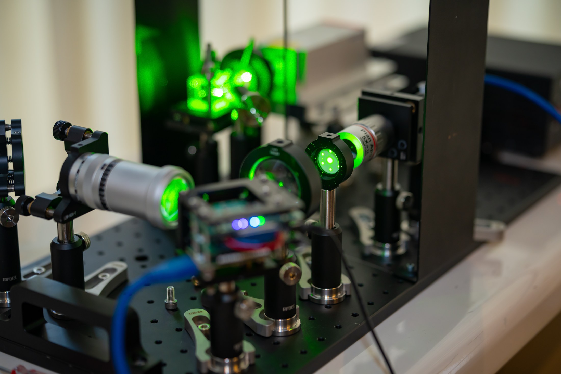 Green-light optical apparatus on a PhotonicsAI experimental table.